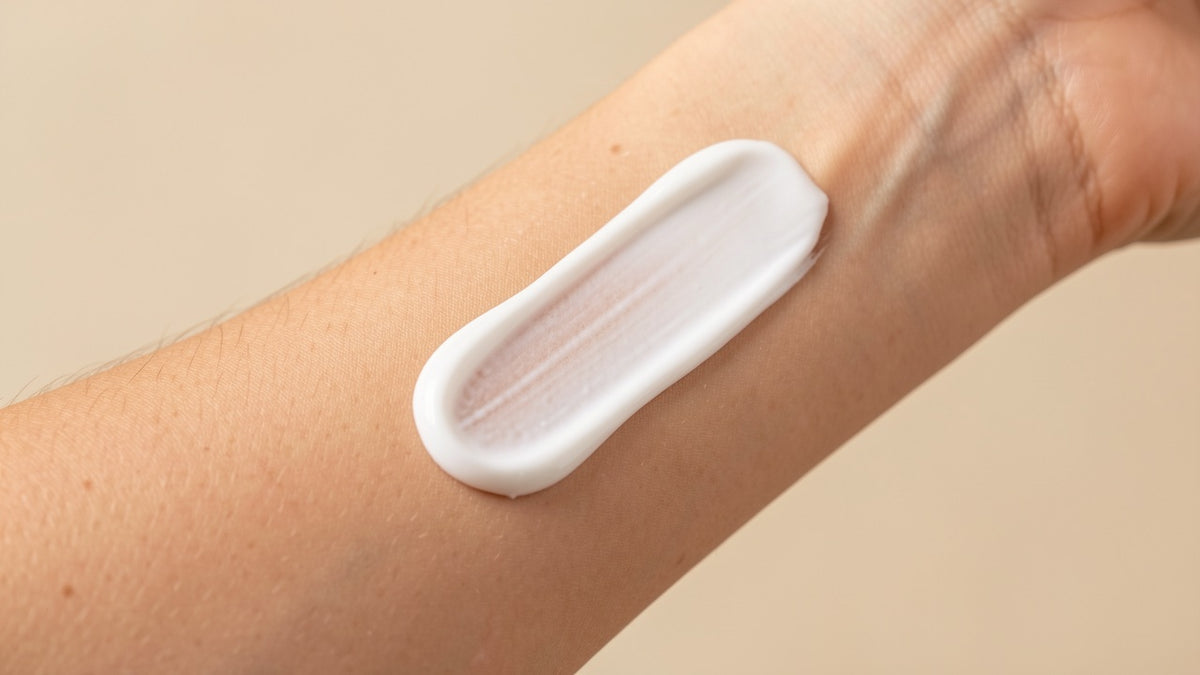 A swipe of white mineral sunscreen cream on the skin of a forearm